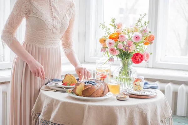 Hora do chá, mãos de mulher segurando panela de chá, flores e bolo — Fotografia de Stock