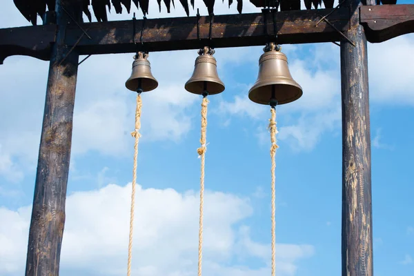 Three metal bells over blue sky