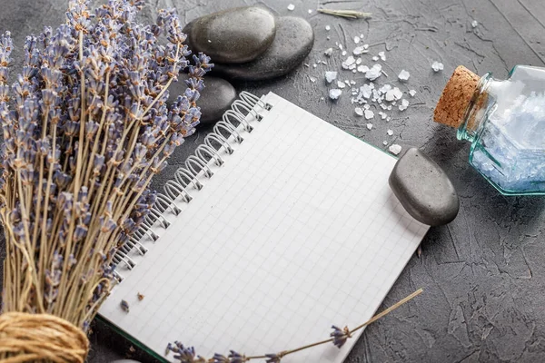 Little notebook, lavender, mineral sea salt and zen stones on a gray stone background.
