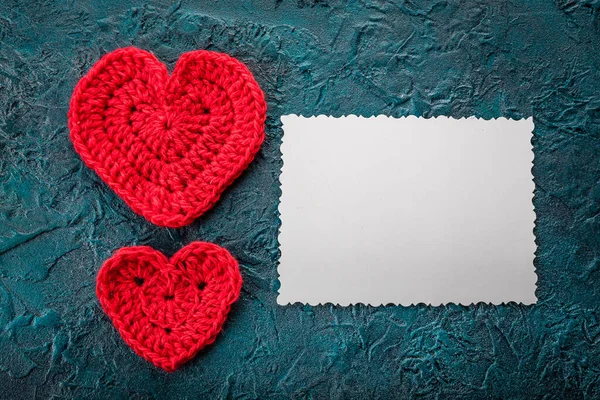 Crochet valentine hearts and greeting card on dark bacground.