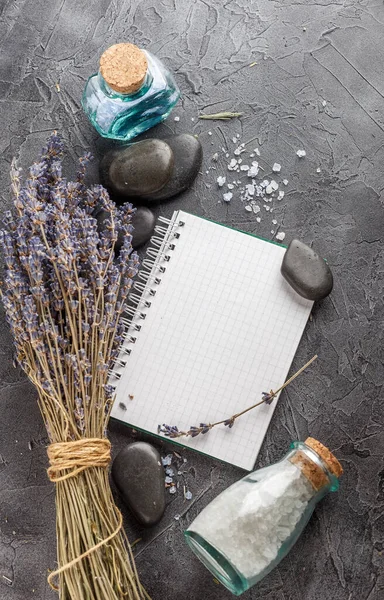 Little notebook, lavender, mineral sea salt and zen stones on a gray stone background.