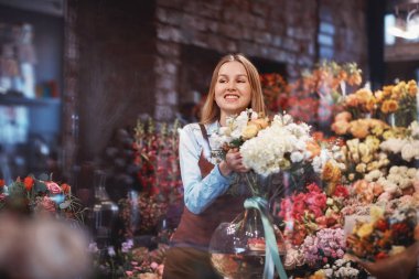 Depodaki çiçekli gülümseyen genç çiçekçi