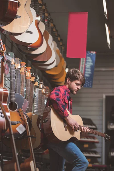 年轻人在商店里弹吉他 — 图库照片