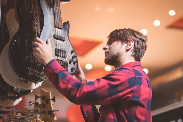 Jovem Escolhe Uma Guitarra Uma Loja — Fotografia de Stock