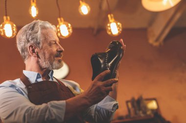 Atölye bir ayakkabı ile gülümseyen yaşlı adam