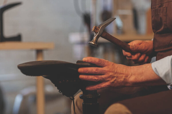 An elderly shoemaker at work in the workshop