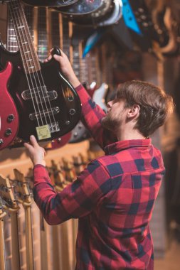 Genç müzisyen bir müzik mağazasında bir bas gitar seçimi