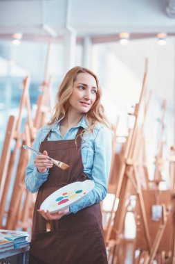 Stüdyoda bir paletle gülümseyen kız