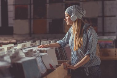 Genç kız bir vinil kayıttaki kulaklıklarla depolamak