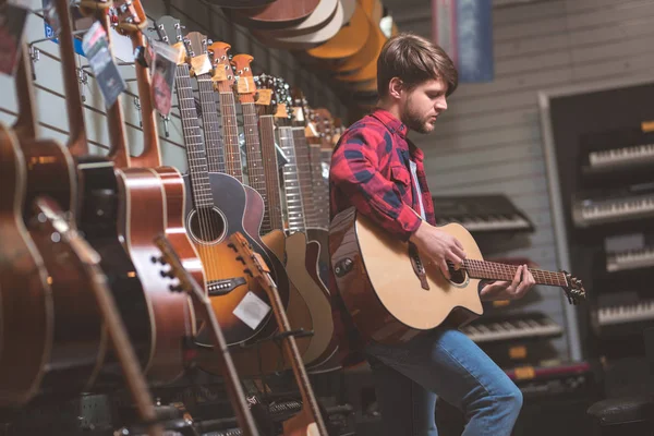 Молодой Человек Играет Гитаре Музыкальном Магазине — стоковое фото