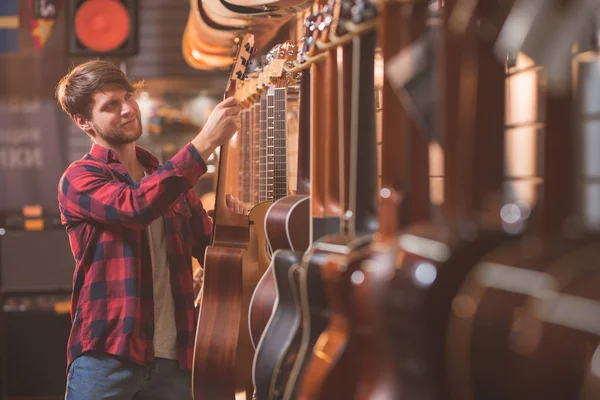 Jovem Músico Escolhendo Uma Guitarra Uma Loja Música — Fotografia de Stock