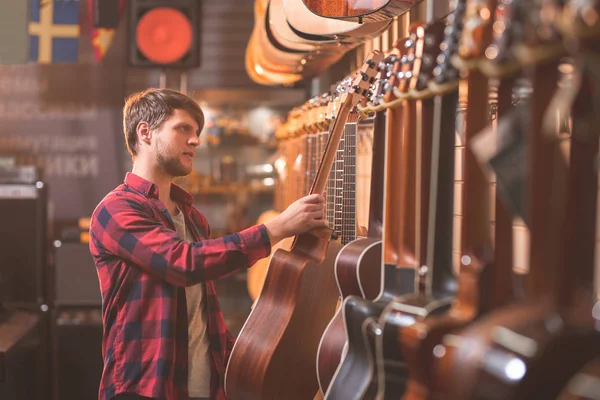 Jovem Músico Escolhendo Uma Guitarra Uma Loja Música — Fotografia de Stock