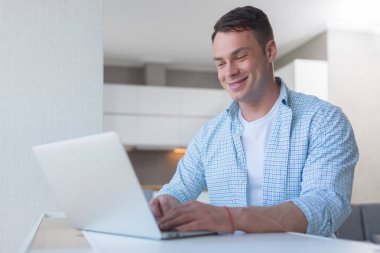 Dizüstü bilgisayar vasıl ev ile gülümseyen genç adam