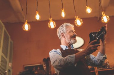 Atölye bir ayakkabı ile gülümseyen yaşlı Ayakkabıcılık