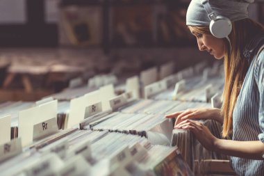 Vinil kayıtlar bir müzik mağazası tarama kulaklık ile genç kız