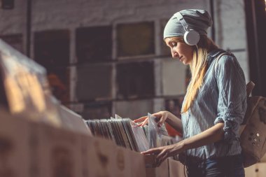 Vinil kayıtlar bir müzik mağazası tarama kulaklık ile genç kadın