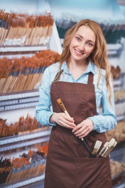 Çekici kız sanat deposundaki bir fırçayla gülümseyen