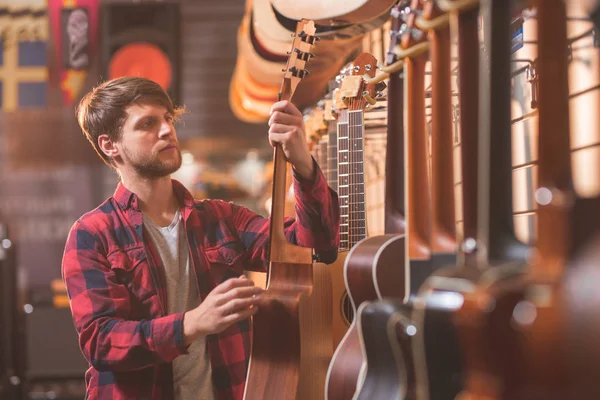 Een Jonge Man Een Gitaar Een Muziekwinkel Kiezen — Stockfoto