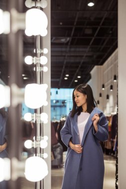 Aynaya bir mağaza, paltolu güzel kadın