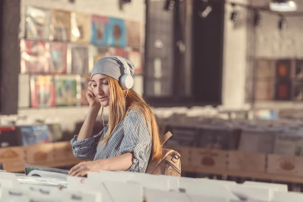 ビニール店でヘッドフォンで音楽を聴く若い女の子 — ストック写真