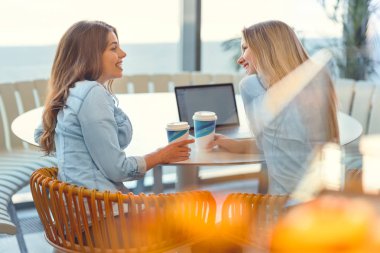 Genç çekici kızlar kafede dizüstü bilgisayar ile