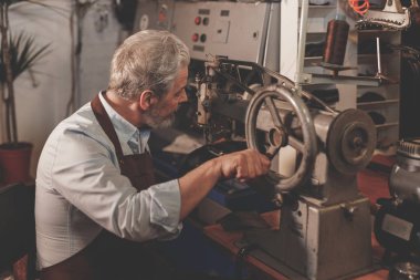 Yaşlı bir adam bir atölyede üniformalı