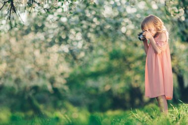 Bir çiçek bahçesinde retro bir kamera ile küçük fotoğrafçı