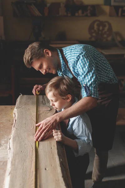 微笑的父亲和儿子测量木工板 — 图库照片
