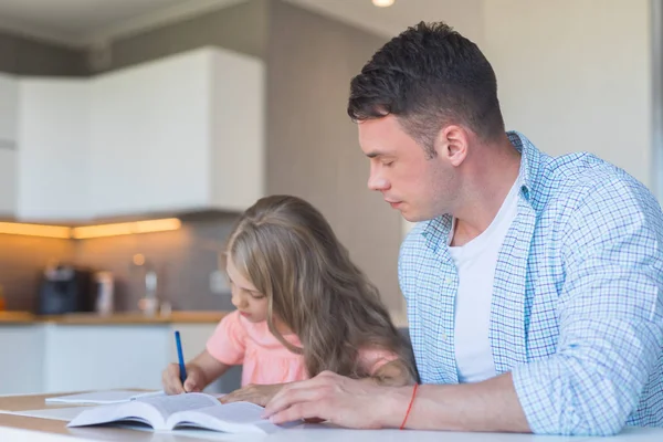 年轻的父亲和一个小女儿在家做家庭作业 — 图库照片