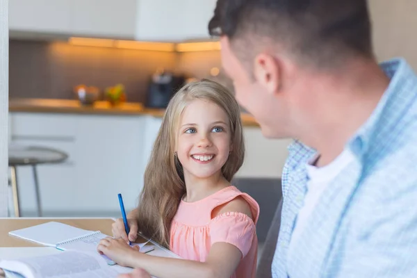 笑顔の父と台所で宿題をしている小さな娘 — ストック写真