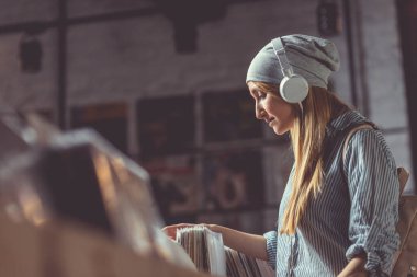 Kayıtları bir müzik mağazası tarama kulaklık ile çekici kız