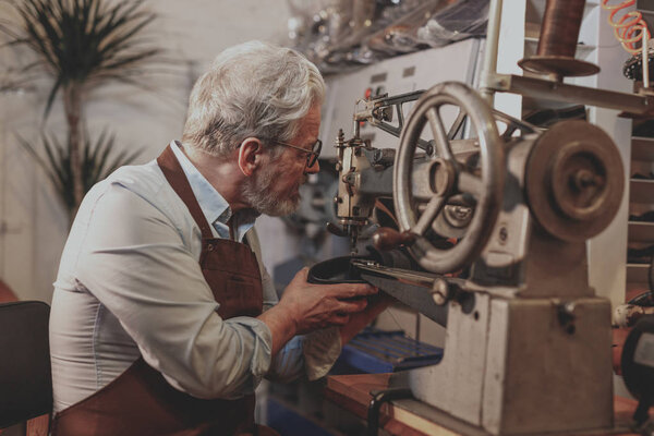 Пожилой мастер за работой в помещении
