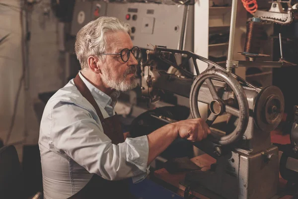 Üniformalı bir atölyede yaşlı bir usta