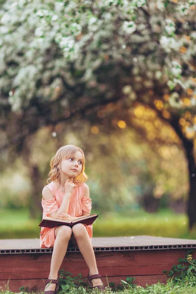 Küçük kız parkta bir kitapla hayal
