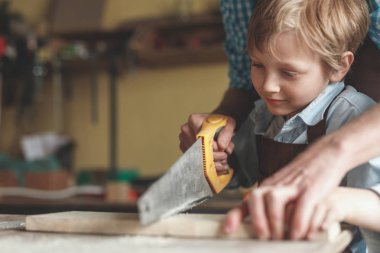 Küçük çocuk bir tahta marangozluk, testere ile kesme