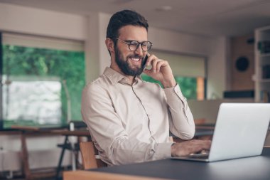 İşyerinde dizüstü bilgisayar ile gülümseyen iş adamı