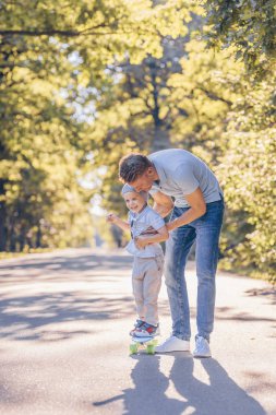 Baba ve oğul parkta bir kaykay ile