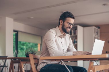 Coworking içinde laptop ile gülümseyen iş adamı