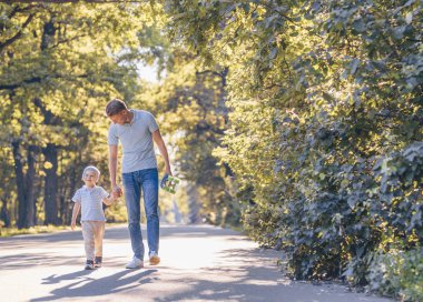 Baba ve oğul parkta bir kaykay ile gülümseyen