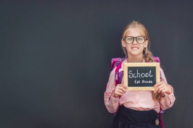 Bir sırt çantası siyah bir arka plan ile mutlu kız