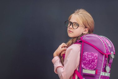 Little schoolgirl with a backpack on a black background clipart