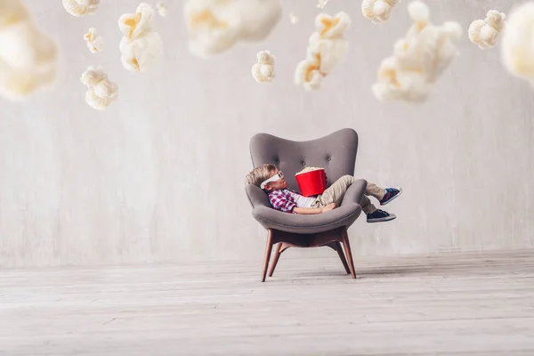 Sleeping little boy with popcorn in cinema