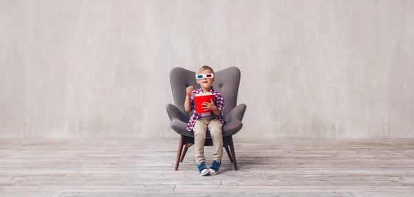 Little boy in 3d glasses with popcorn in cinema