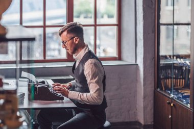 Working man with a retro typewriter in the office clipart