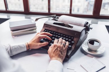 Young writer typing on a retro typewriter close-up clipart