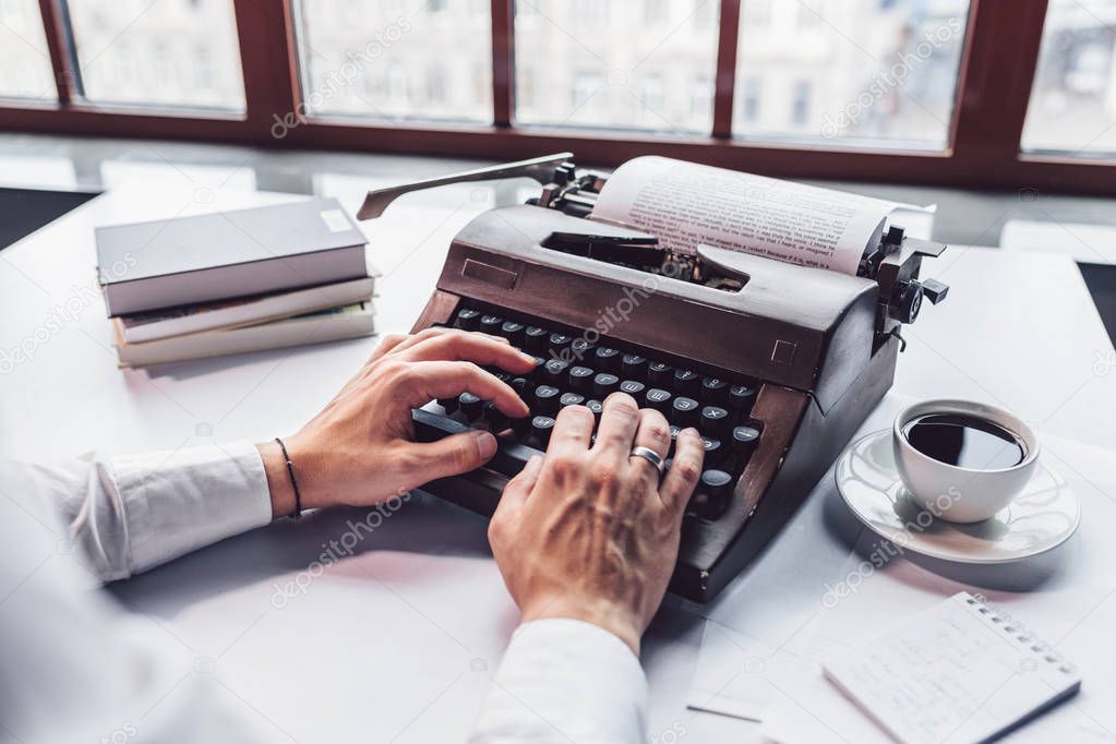 Young writer typing on a retro typewriter close-up