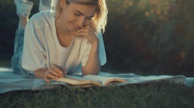 Çekici kız günbatımında bir kitap okuma