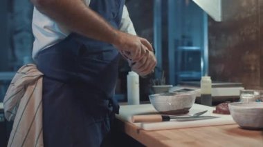 Genç aşçı mutfakta yemek pişiriyor.