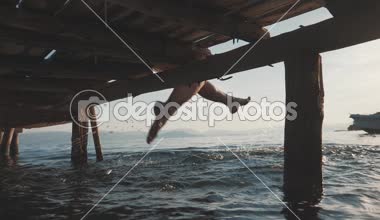 Kız bacaklarını denizde sallanan