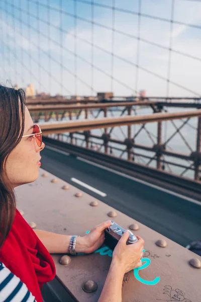 有吸引力的女孩与相机在布鲁克林大桥在纽约 — 图库照片